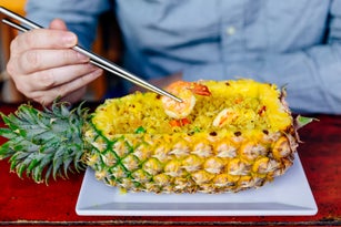 Man eating rice with seafood served in a pineapple with chopsticks
