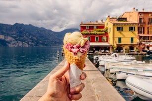 Eating colourful gelato ice cream among vibrant houses in Malcesine town, Garda Lake, Italy