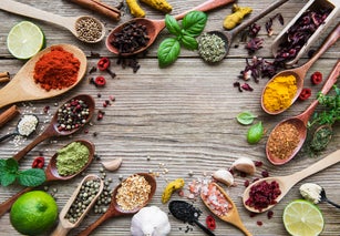 A selection of various colorful spices on a wooden table in  spoons
