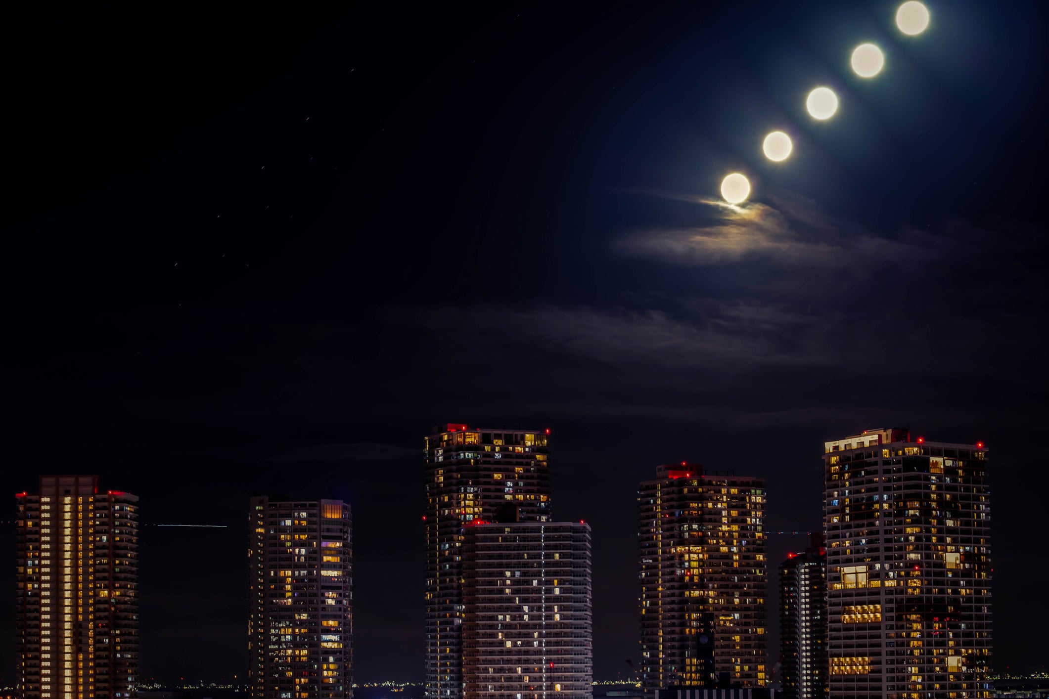 Tokyo cityscape with residential buildings and moon at night.