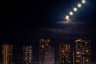 Tokyo cityscape with residential buildings and moon at night.