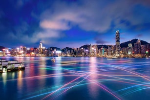 The world famous night scene of Hong Kong city skyline with busy water traffic navigate across Victoria Harbour