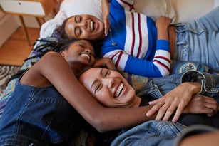 Young female friends lying on bed at home
