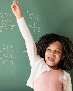 African American student cheering near chalkboard in classroom