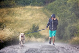 Man with dog running together in heavy rain
