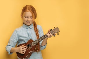 beautiful girl play ukulele isolated