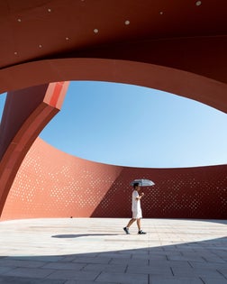 Someone holding an umbrella in red curved abstract architectural space
