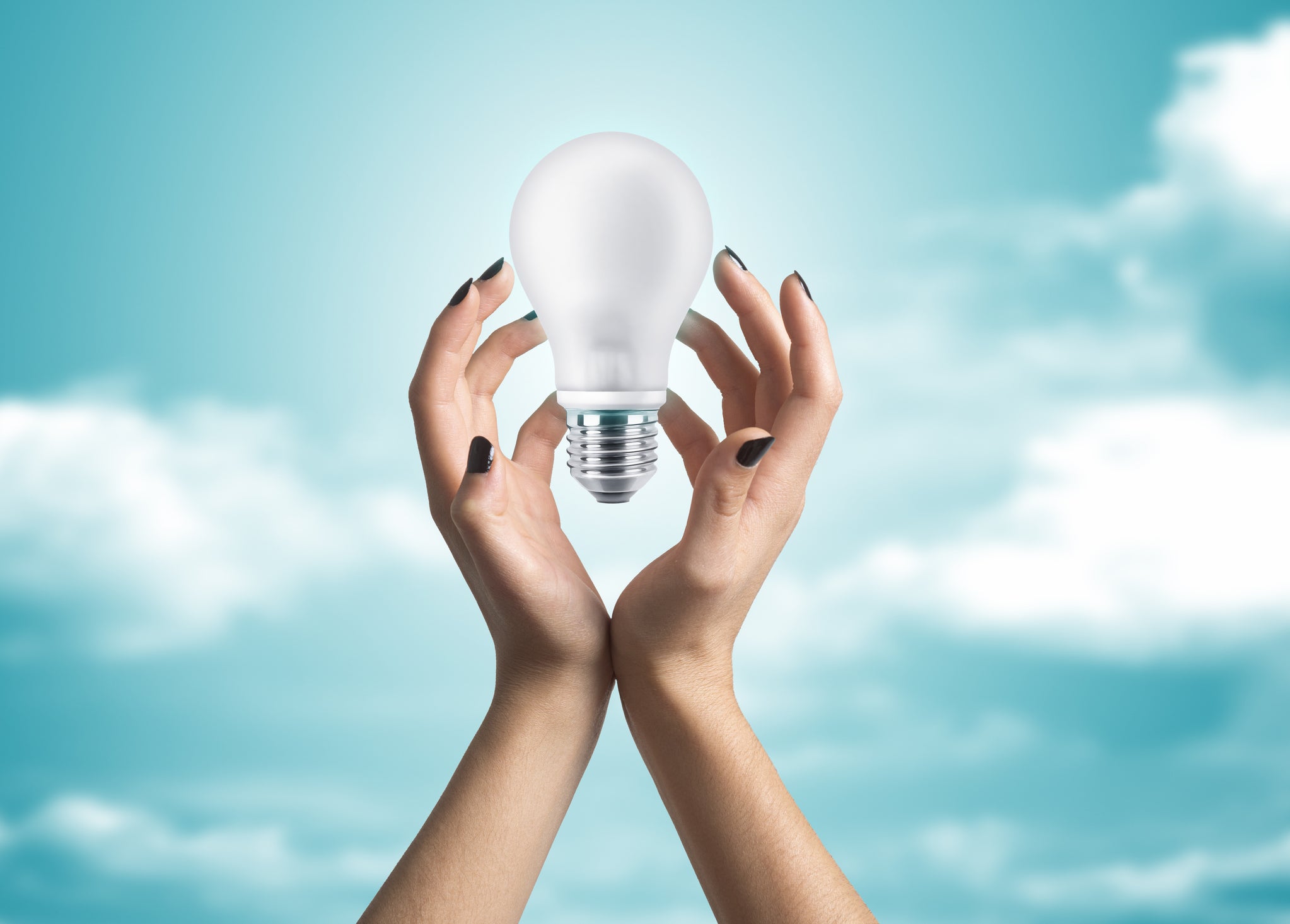 Woman's hands holding a white light bulb