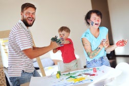 Young parents play with a small child at home, draw, have fun. Happy family