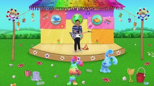 Josh is standing on a stage. Blue, Rainbow Puppy and Slippery Soap are on the grass nearby. There is a lot of litter scattered all over the ground.
