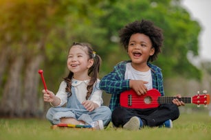 Little girl happiness play with toy block and little boy trying to play with ukulele, kid learning with wooden block and music for education