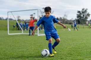 Kid in field playing soccer game.
