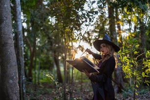 Captivating image of a Caucasian female in a witch costume, set in a dark, enchanted forest during Halloween. Experience the magic and mystery of this mystical, fairytale-inspired scene.