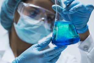 Researcher watching chemical reaction after adding test material into flask