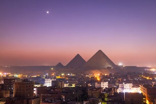 the stark contrast between the city of Cairo and the iconic Pyramids make for a stunning view during the blue hour, Cairo, Egypt, Africa