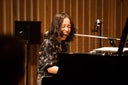 An artist playing the piano while laughing