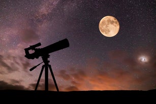 Telescope on the background of the starry sky and moon. Amateur astronomy and space exploration