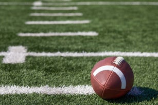 American football ball at yard line markers on playing field