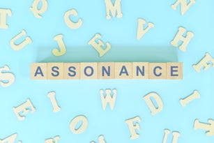 Assonance figure of speech figurative language concept in English grammar class lesson. Wooden blocks typography flat lay in blue background.