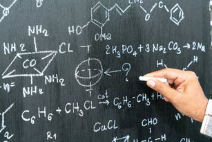 Blackboard inscribed with scientific formulas and calculations in physics.