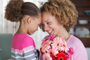 Black mother and daughter holding bouquet of flowers