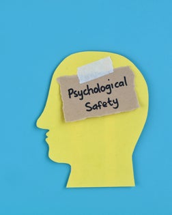 Psychological safety concept handwritten with human head paper silhouette on blue background