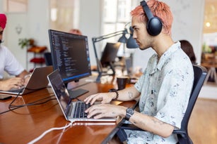 Young man wearing headphones working on computer at startup office