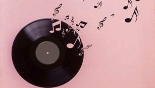 Vinyl record on pink background. Several musical notes are born of the vinyl record