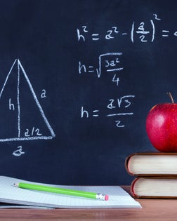 Apple on book and green wooden pen on opened notebook on desk