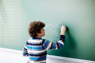 Boy writing on board in school class