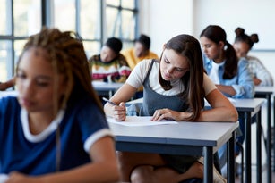 Young multi-ethnic female students writing exam