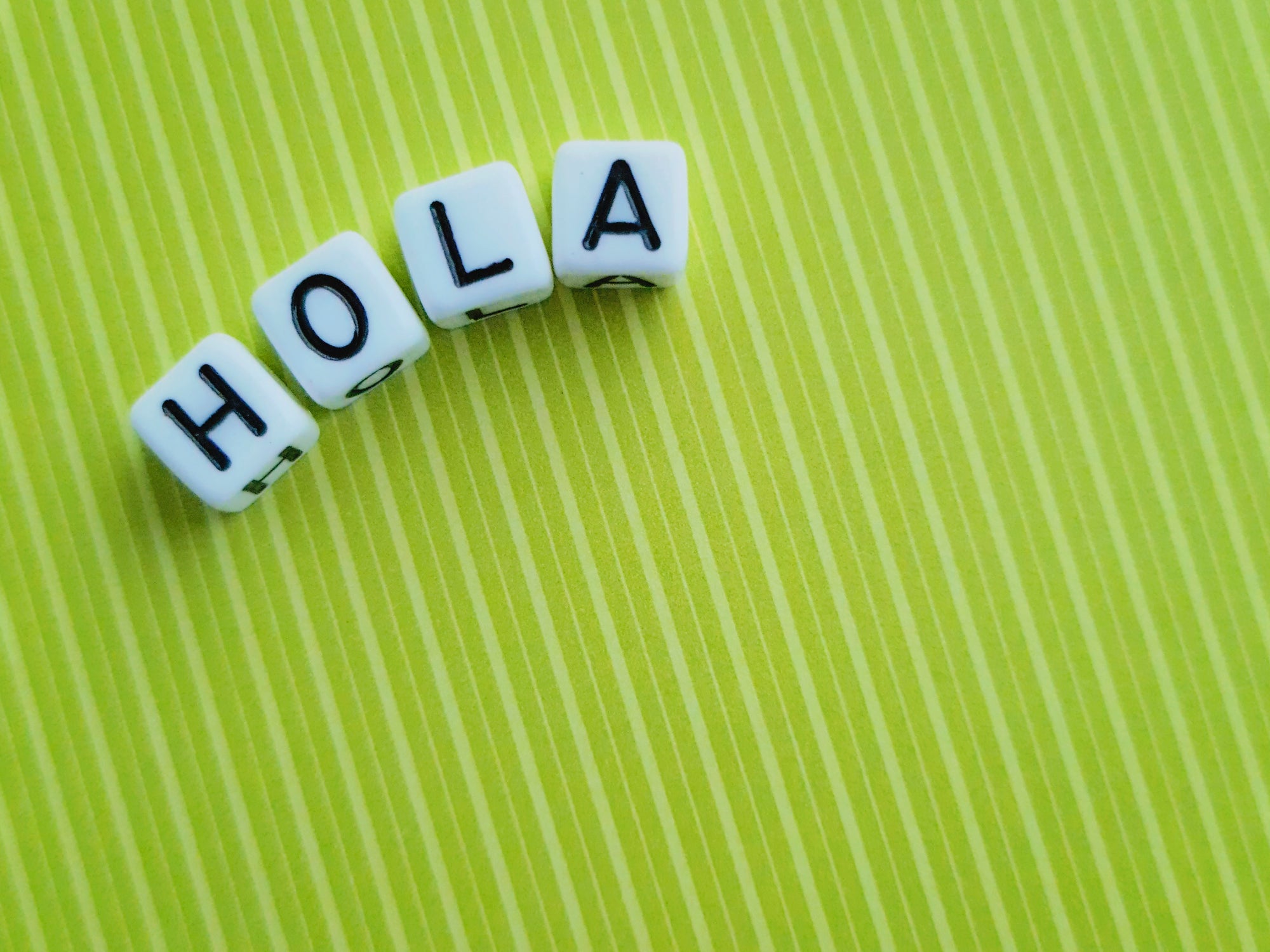 Word "Hola" (Hello in Spanish language) on Green Background