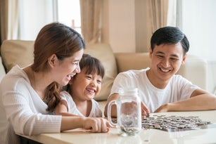 Family saving money putting coins into piggy bank