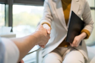 Businesswoman and businessman shaking hands in modern office.