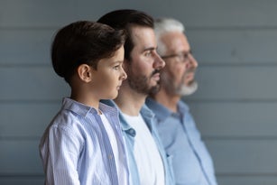 Serious thoughtful boy kid standing in row with young fath
