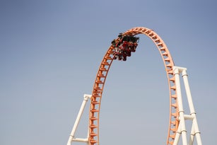 Roller coaster at the peak of a loop against a clear blue sky