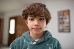 Portrait of a 7 year old boy looking at camera with slightly long hair at home