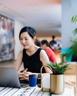 Young Asian businesswoman working in a modern office space while talking in front of the camera having video conference with her business partners on laptop. Virtual business meeting. Making business connections with technology