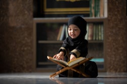 Muslim children reading Al Quran in mosque.
