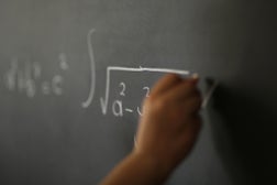 Hand Holding Chalk and Writing Complex and Sophisticated Mathematical Formula/ Equation on the Blackboard.