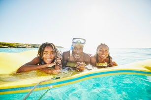 Medium shot smiling father and daughters relaxing on swim float in ocean