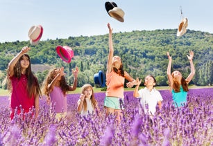 Joyful kids tossing up hats in lavender field