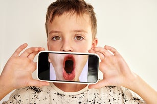 Boy holding smartphone displaying open mouth screaming