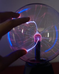 Hand touching a plasma ball at a science museum