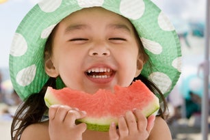 Asian girl eating watermelon at beach
