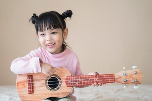 Asian cute child girl play guitar with happiness. music concept.