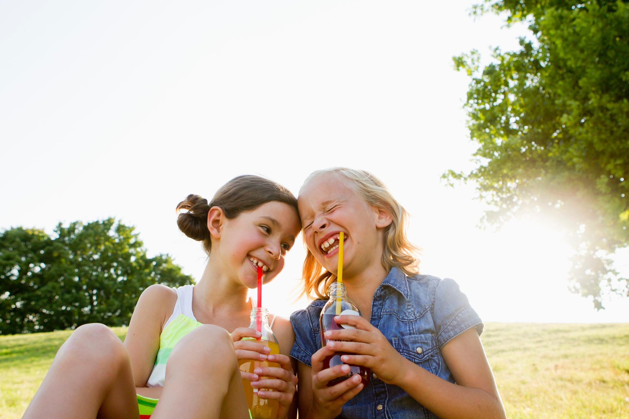 Laughing girls drinking juice outdoors