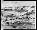 Photograph of DDay invasion showing landing craft, tanks, soldiers, and blimps.