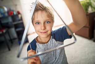 Cute little boy playing triangle at home