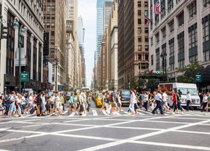 Numerous people crossing a street in New York City.